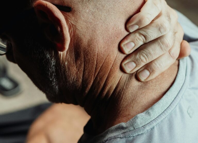 Man with neck pain holding his neck in discomfort, conveying tension or stress.