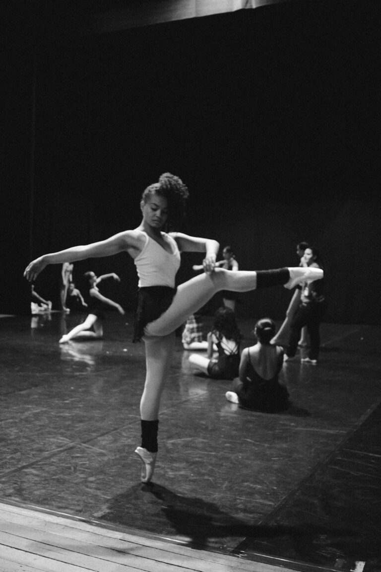 Black and white image of diverse ballet dancers practicing in a studio, showcasing grace and skill.