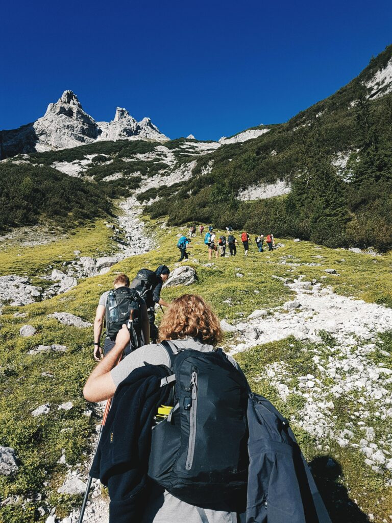 A group of hikers trekking through the rugged landscape of Garmisch-Partenkirchen, Germany under a clear blue sky.